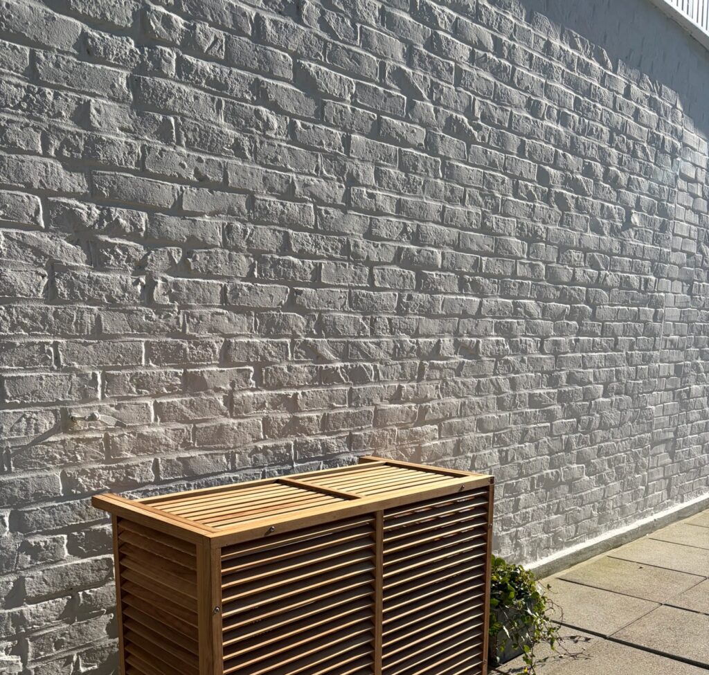 Cache en teck posé contre un mur en pierre sur une terrasse