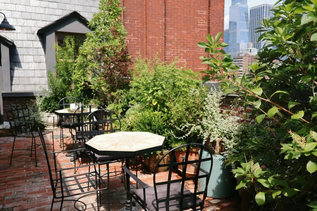 A serene rooftop patio in New York City featuring lush garden plants and cozy seating.